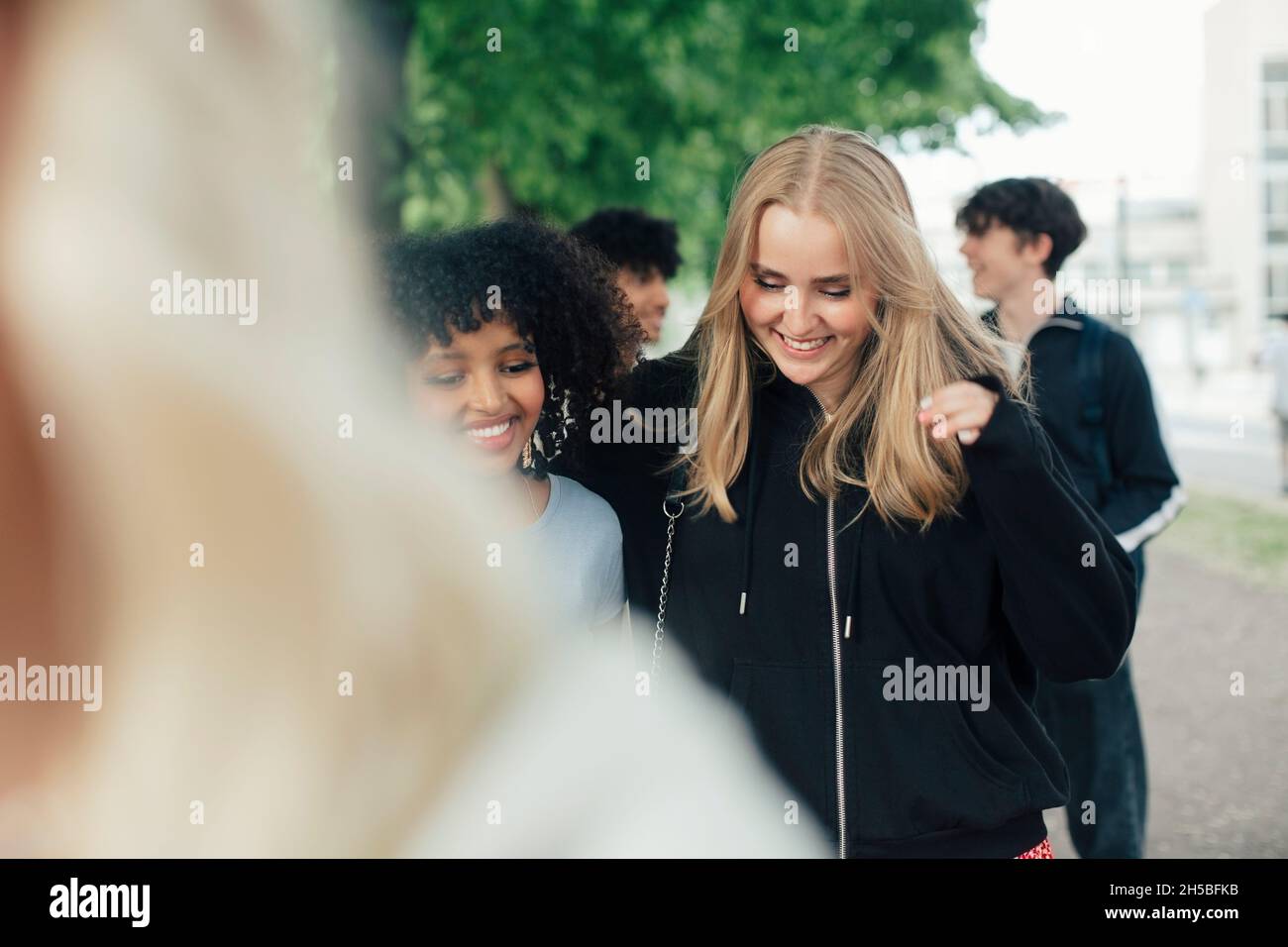 Happy female and male friends hanging out in park Stock Photo