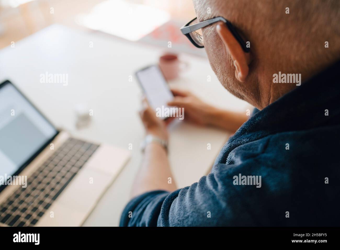 Senior man using smart phone at home Stock Photo