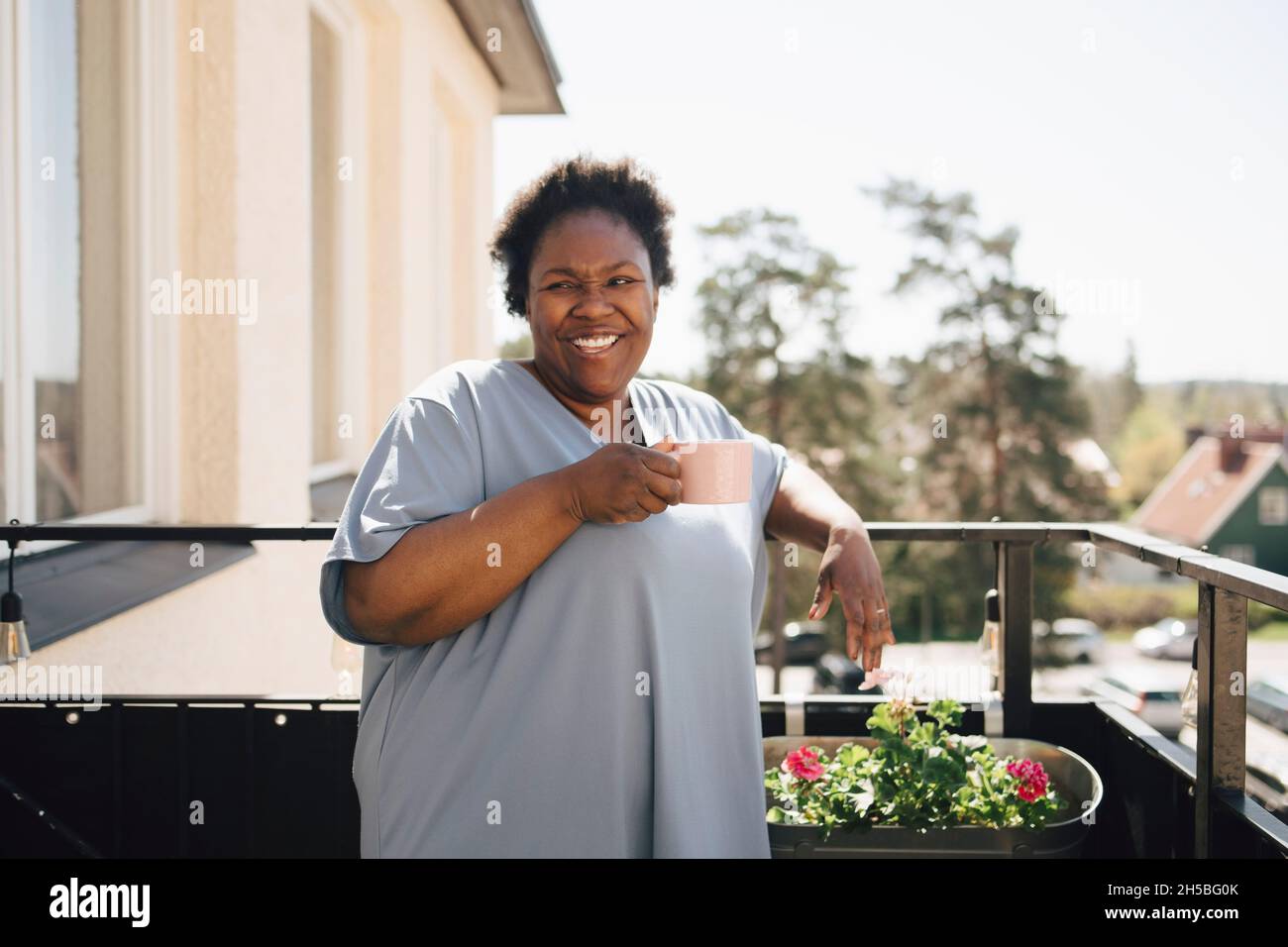 Happy woman having coffee in balcony Stock Photo