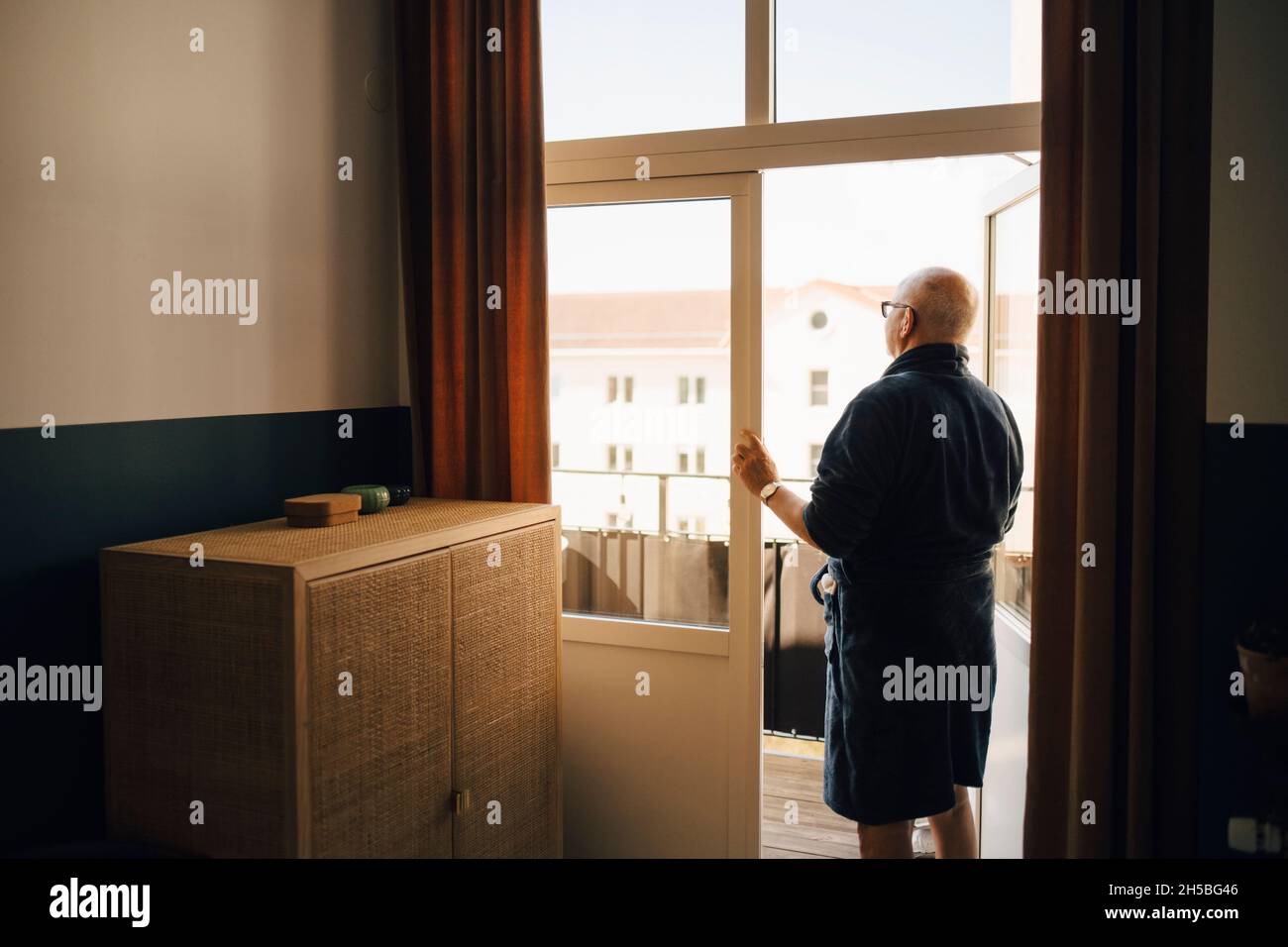 Senior man looking out while standing in doorway Stock Photo