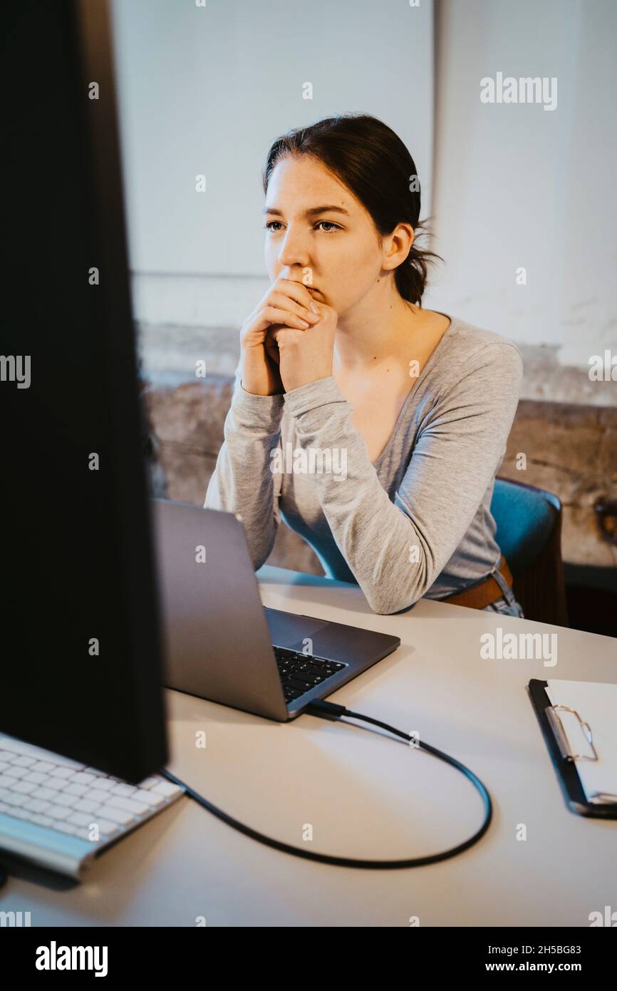 Young female programmer brainstorming over computer in office Stock Photo