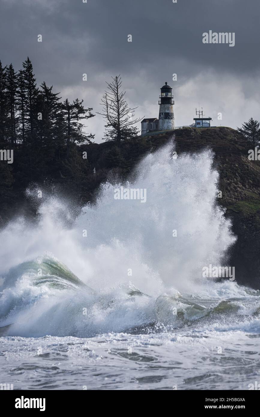 Massive waves crashing under scenic light house during king tide storm on the Washington Coast, Cape Disappointment State Park, Pacific Northwest Stock Photo