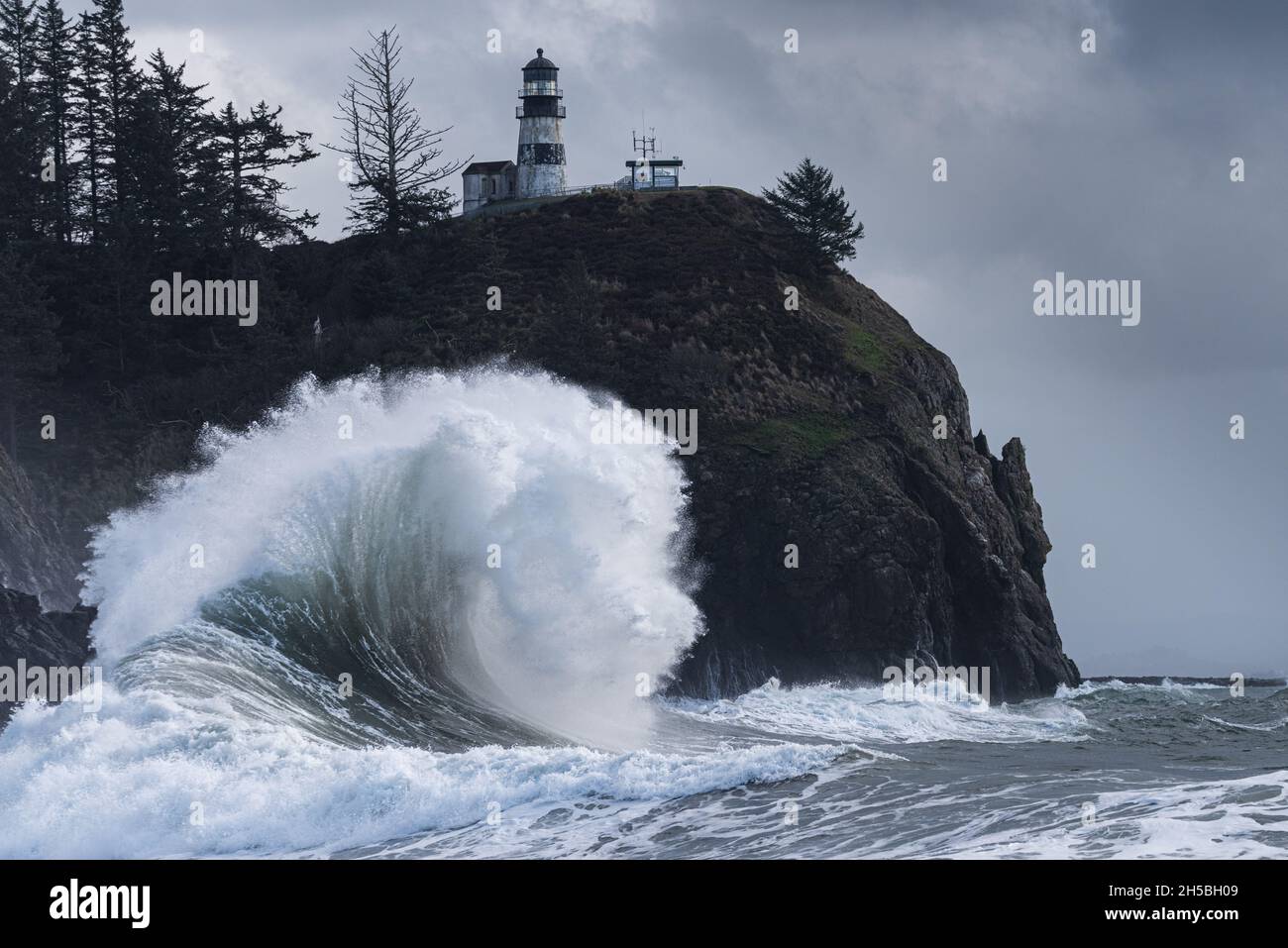 Massive ocean wave crashing under lighthouse during stormy king tides
