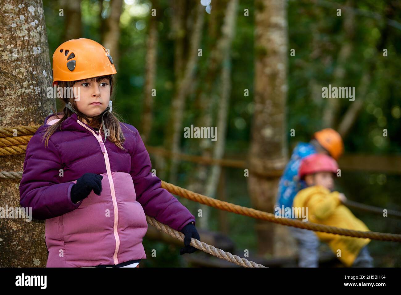 adventure climbing high wire park - people on course in mountain helmet and safety equipment. Stock Photo