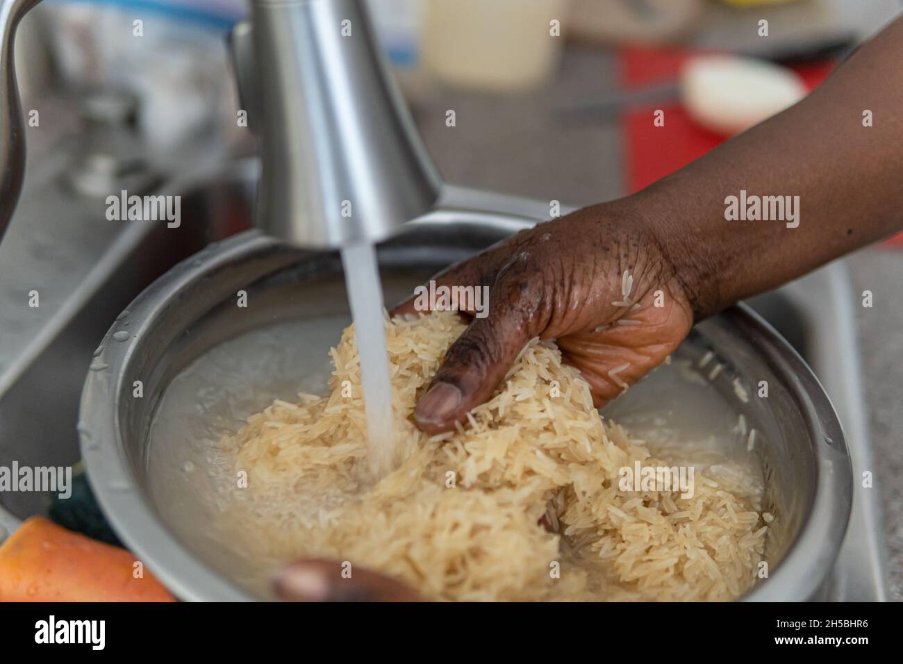 African American Nigerian woman washing rice before cooking Stock Photo