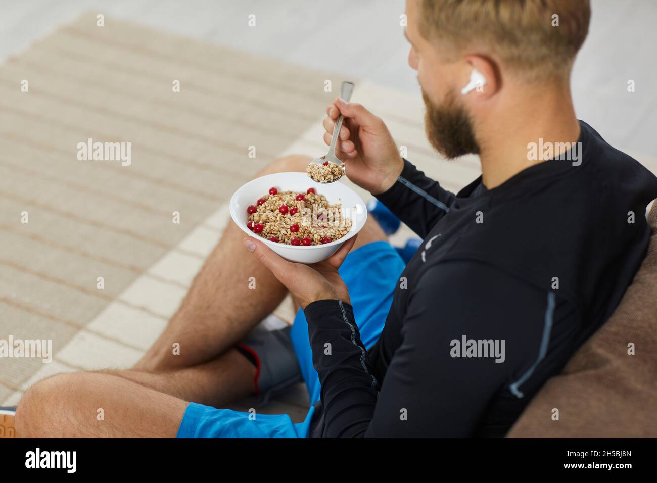 Young male athlete is having a bowl of healthy granola after his fitness workout Stock Photo