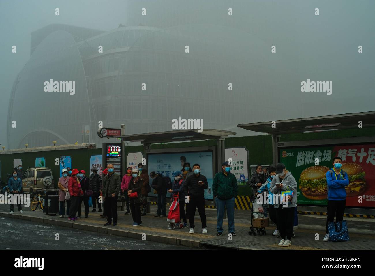 People wait for the bus in Beijing's central business district shrouded by heavy smog in Beijing, China.06-Nov-2021 Stock Photo
