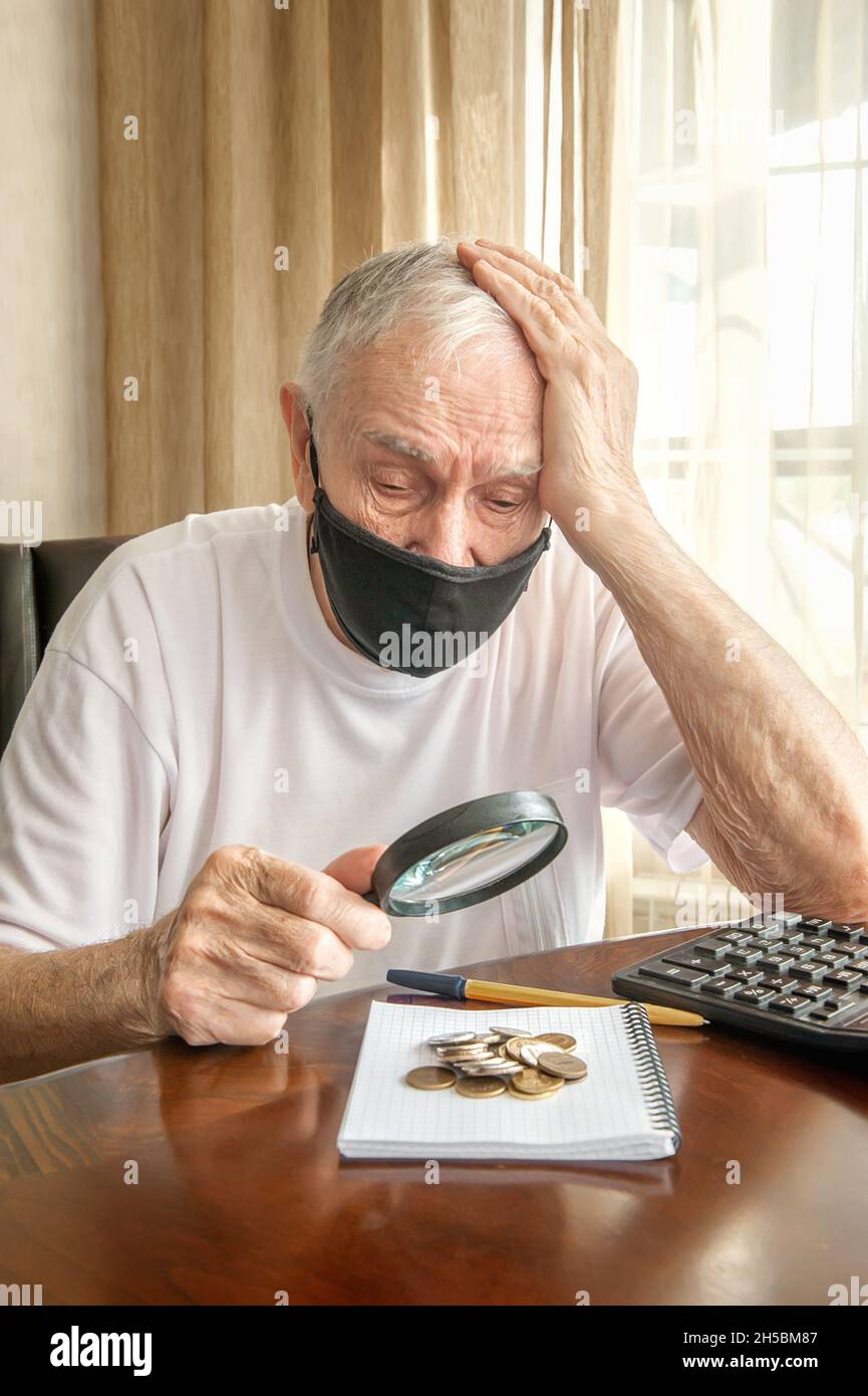 old man in a medical mask is sitting at home in quarantine and counting ...