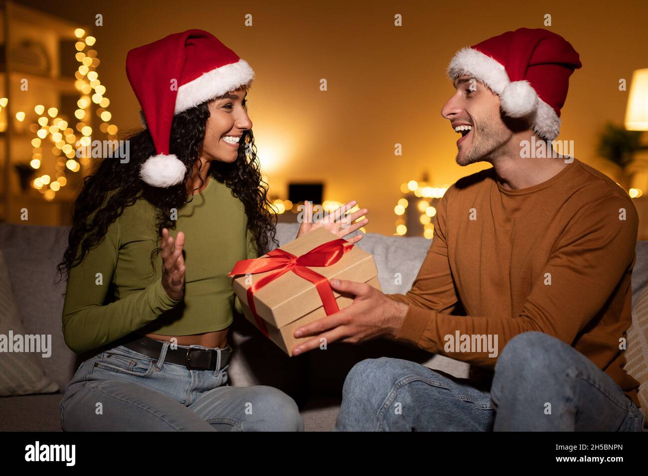 Husband Giving Christmas Gift To Wife Congratulating Her At Home Stock