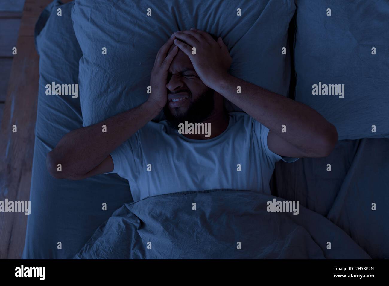 Black man suffering from headache or migraine at night Stock Photo Alamy