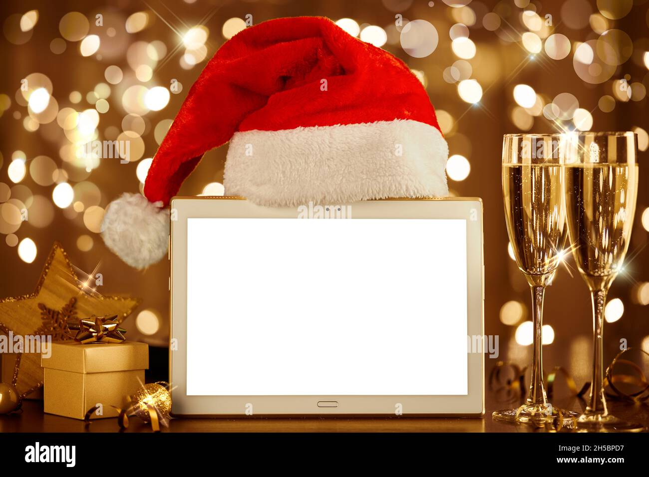 Christmas mockup. Blank tablet and Santa hat on blurred background of winter holiday. Stock Photo