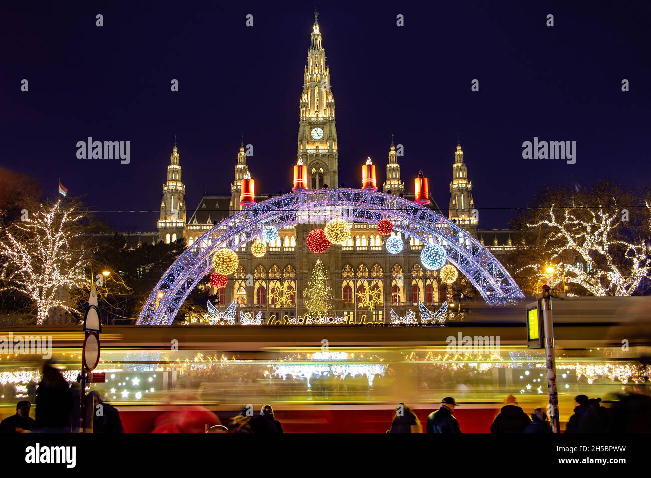 The tram is ride in front of the Christmas market by City hall -  Rathaus in night Vienna, Austria. Stock Photo