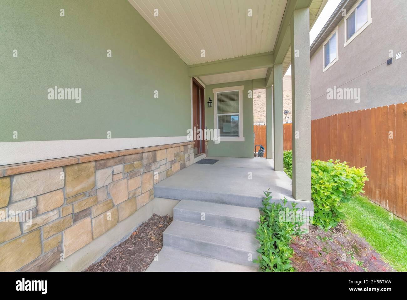Concrete doorsteps at the side of a house with brown door Stock Photo