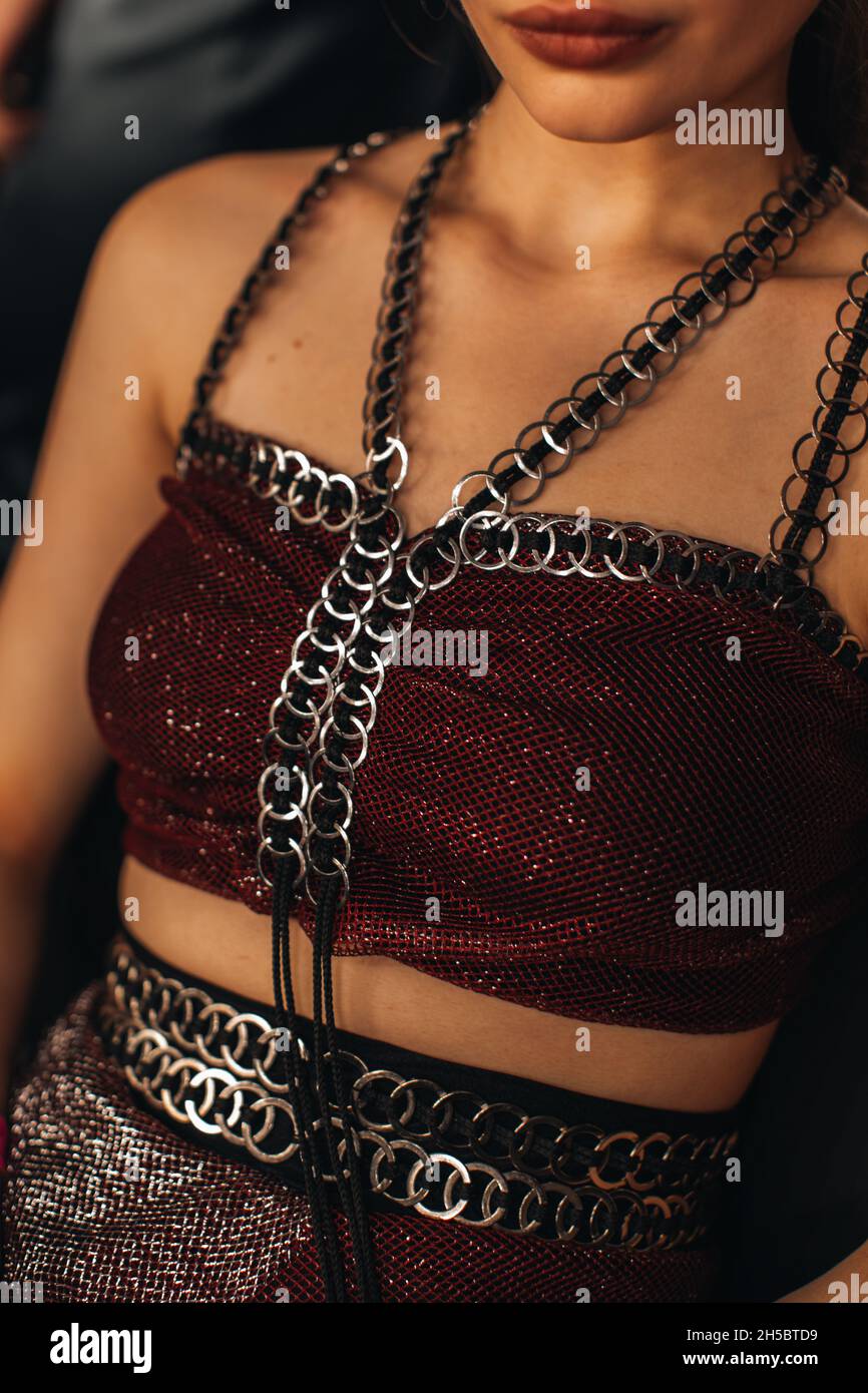 Detail of a female body dressed in a stylish red top with metal chains Stock Photo