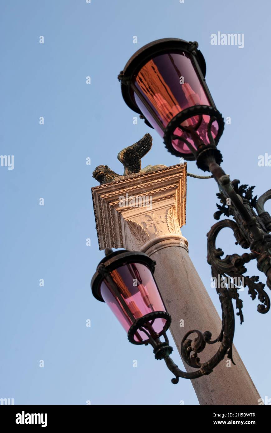 Close-up of a streetlight in the square in Venice, and in the background the winged lion, a symbol of the city Stock Photo