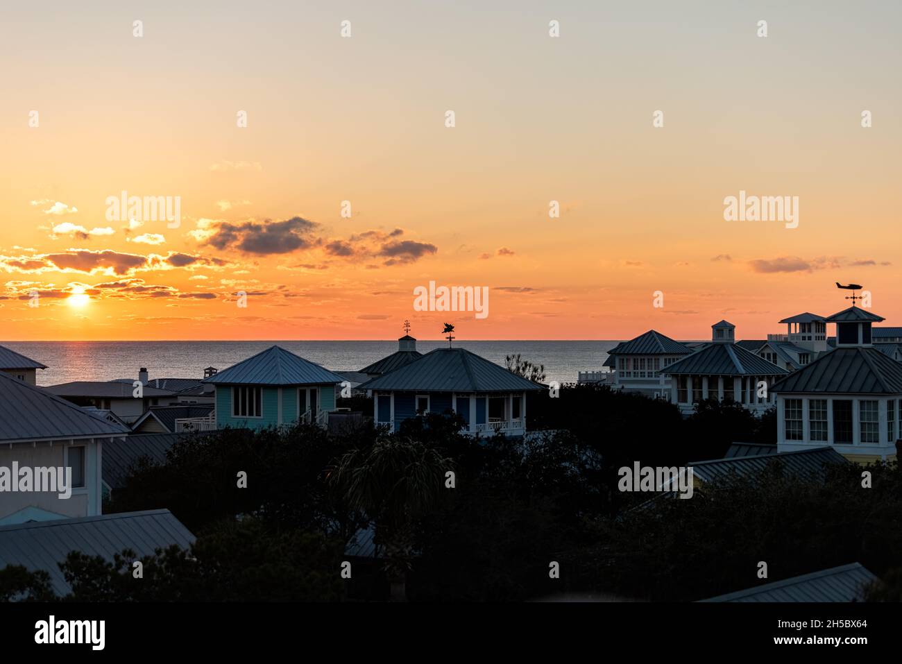 Aerial view on colorful yellow sunset sun with ocean landscape of Gulf of Mexico in Seaside, Florida from rooftop terrace buildings houses cityscape a Stock Photo