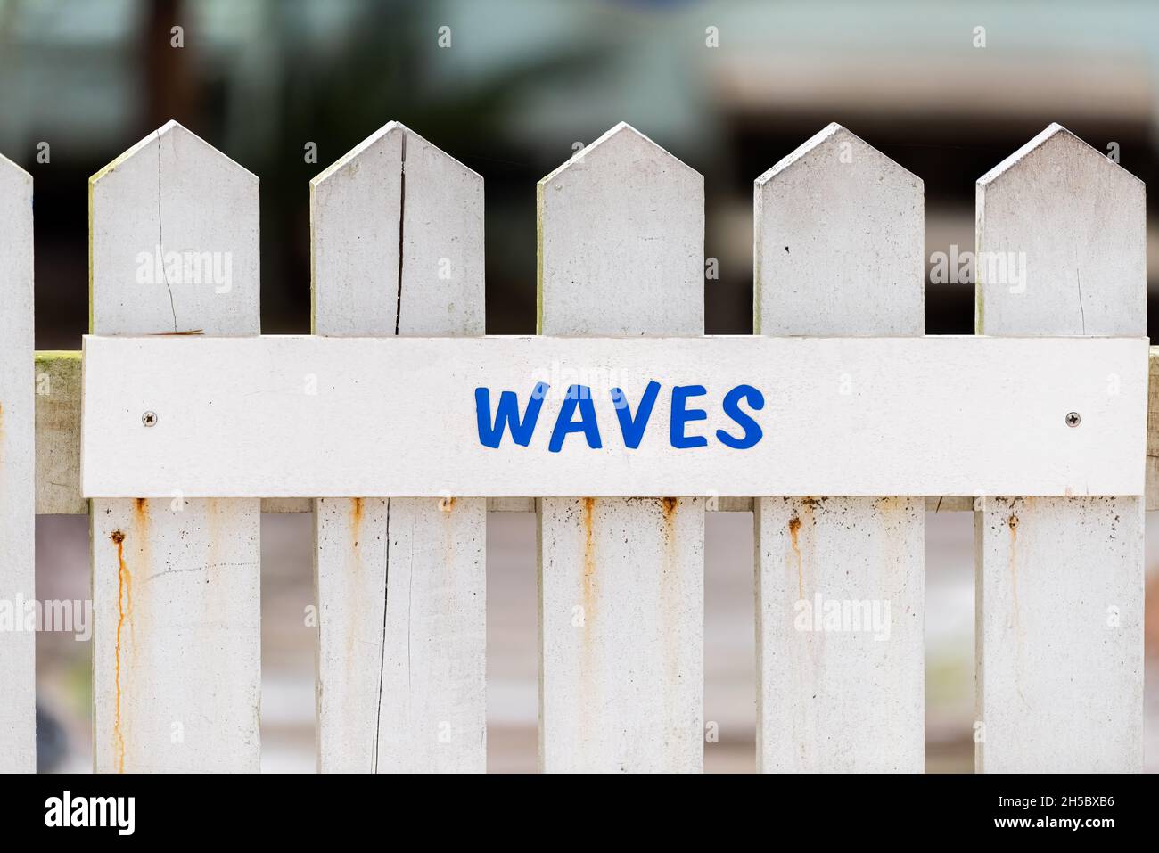 White wooden wood architecture of house and door gate to home beach cottage closeup with blue sign in English for waves Stock Photo