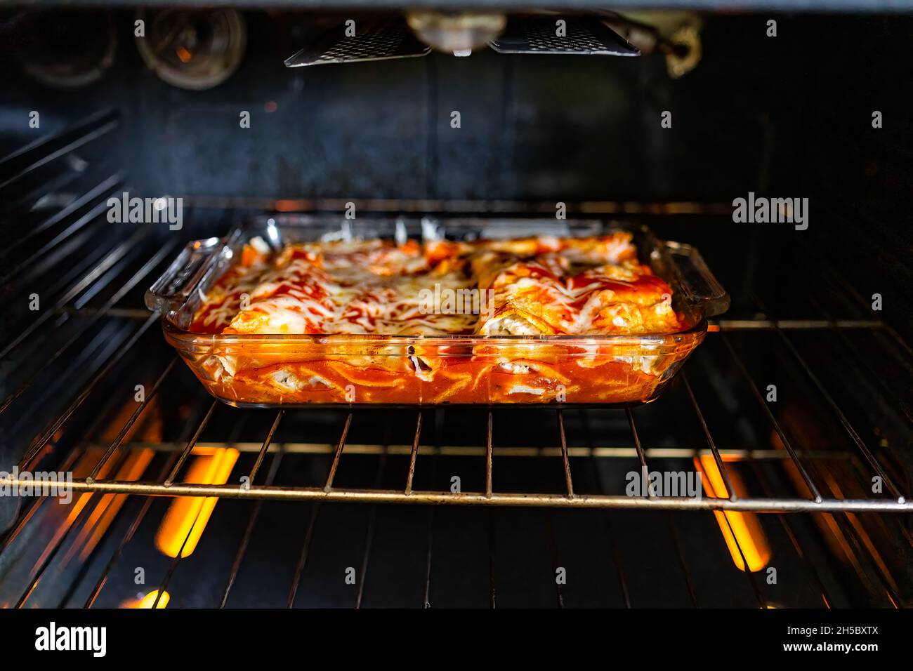 Inside oven with rack and homemade Mexican food enchiladas in baking