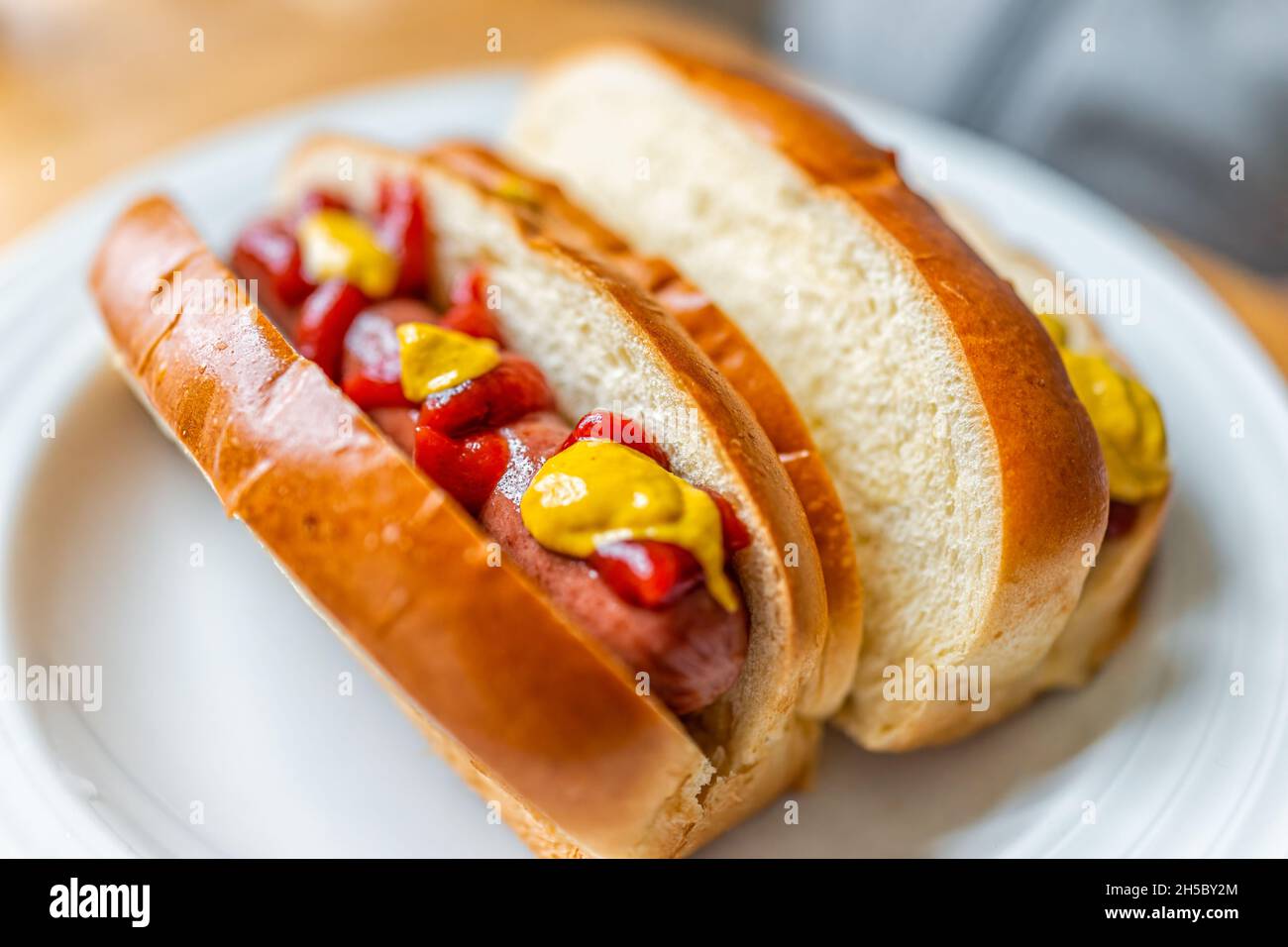 Hot dog sausage cooked prepared on brioche bun with ketchup and mustard