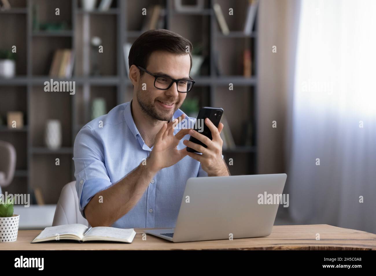 Happy handsome young man using cellphone in office. Stock Photo