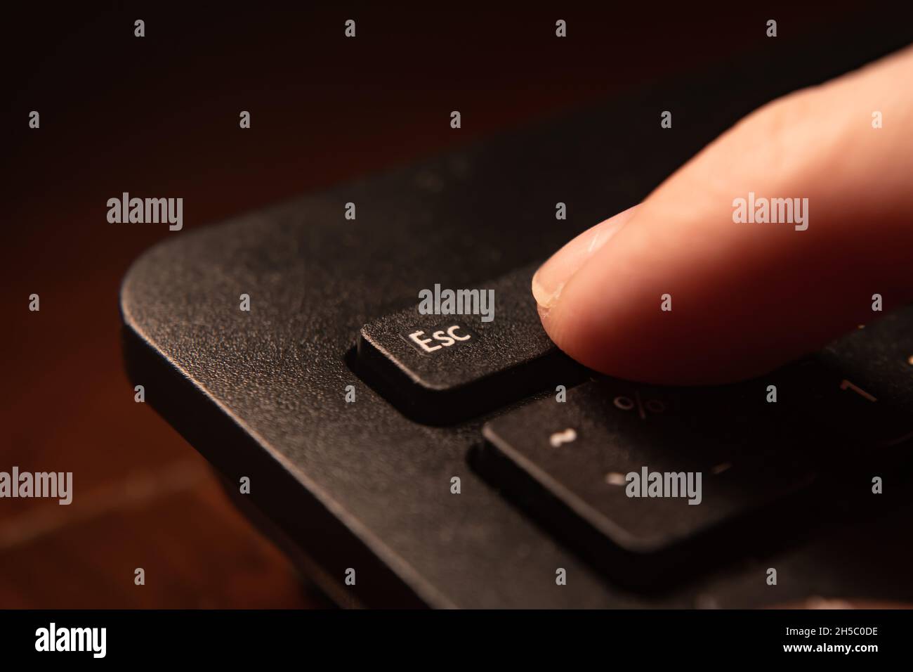 The index finger pressing on the Esc key Stock Photo