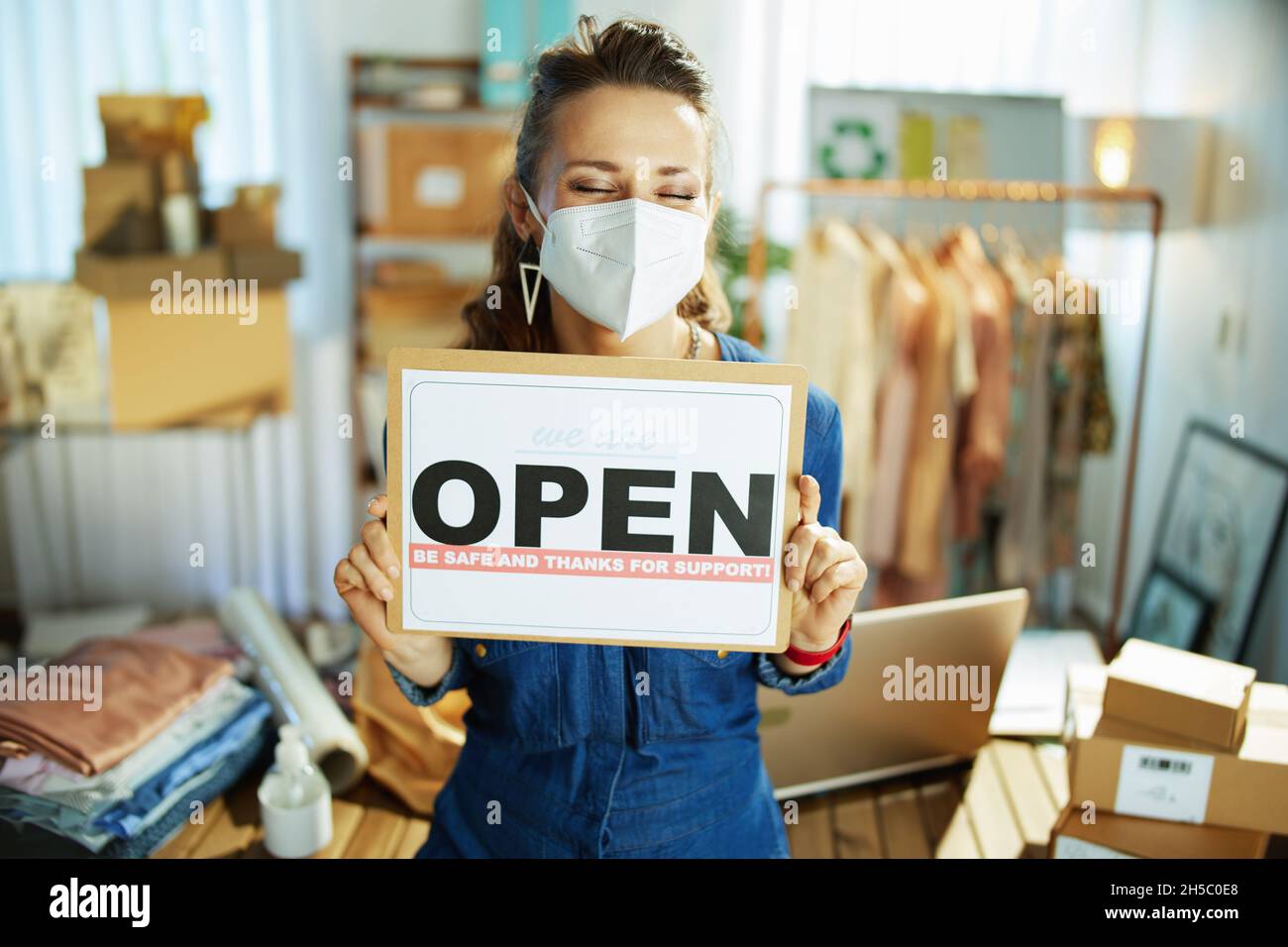 stylish 40 years old small business owner woman with ffp2 mask and open after covid sign in the office. Stock Photo
