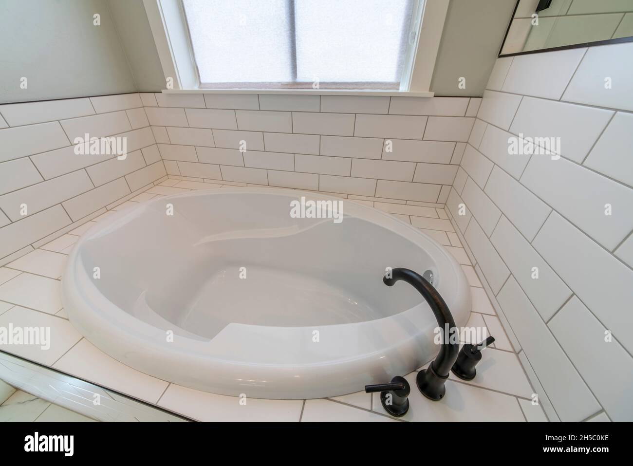 Alcove bathtub with deck mounted faucet and subway tiles surround Stock