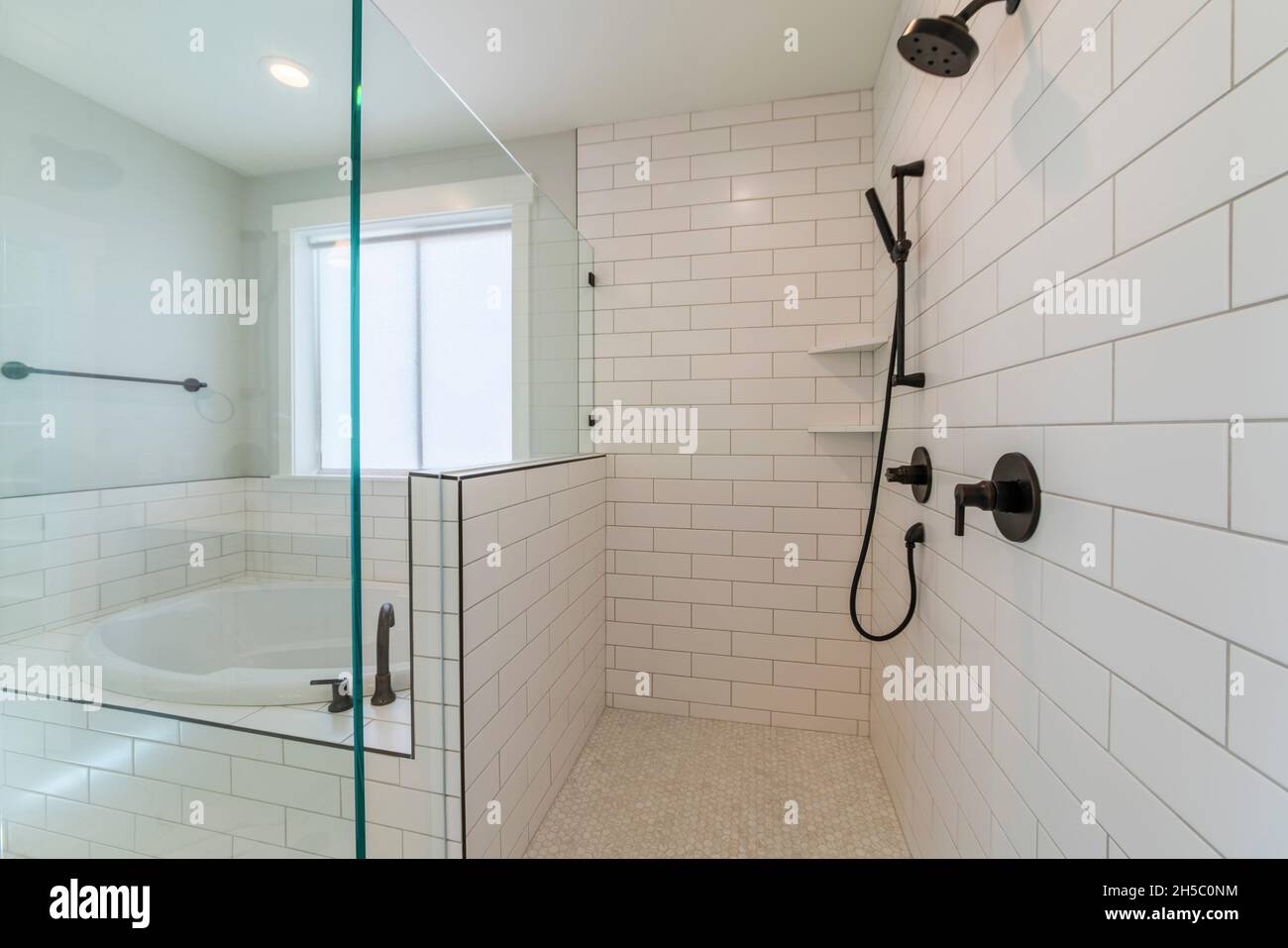 Bathtub and shower stall inside a bathroom with subway tiles surround