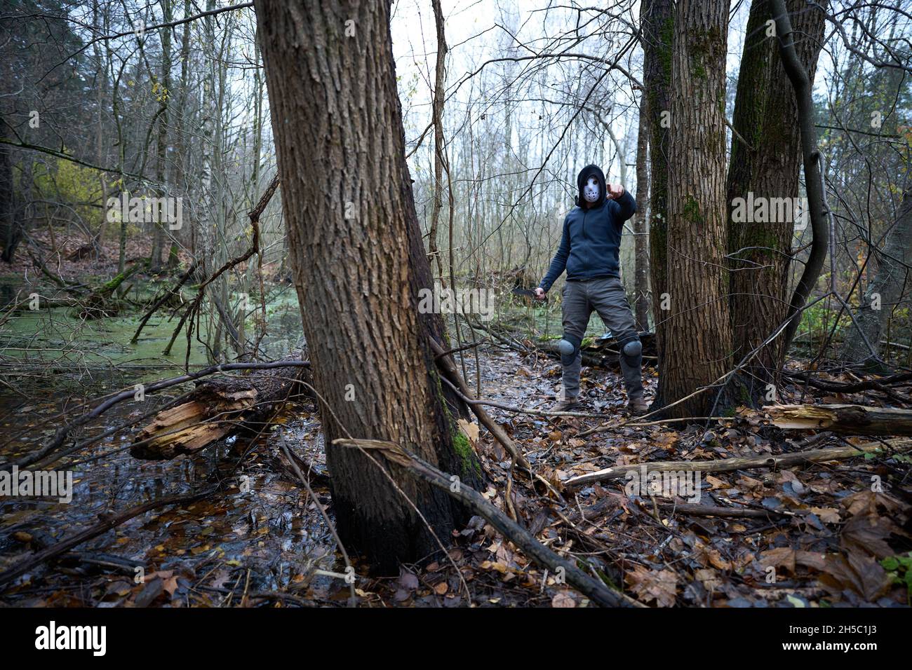 Serial killer Jason Voorhees in hockey mask at the swamp in the autumn forest. Friday 13h cosplay costume.  Stock Photo