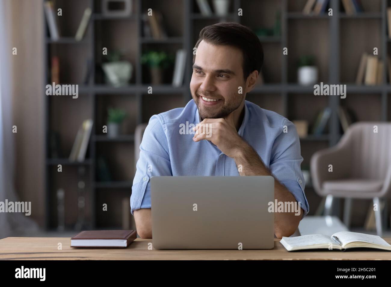 Distracted from computer work young businessman looking in distance. Stock Photo