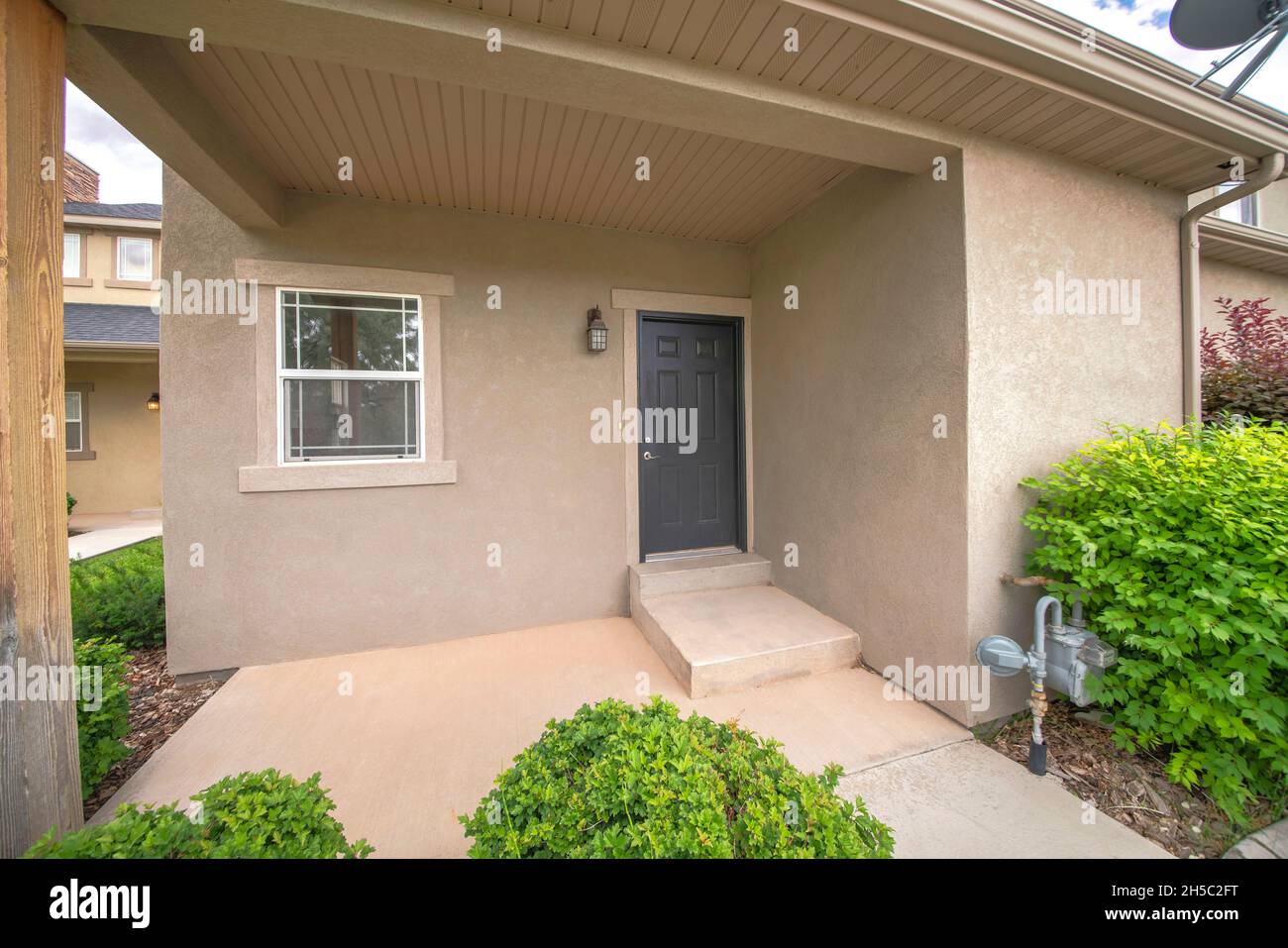 Entrance of a house with black front door and concrete doorsteps Stock