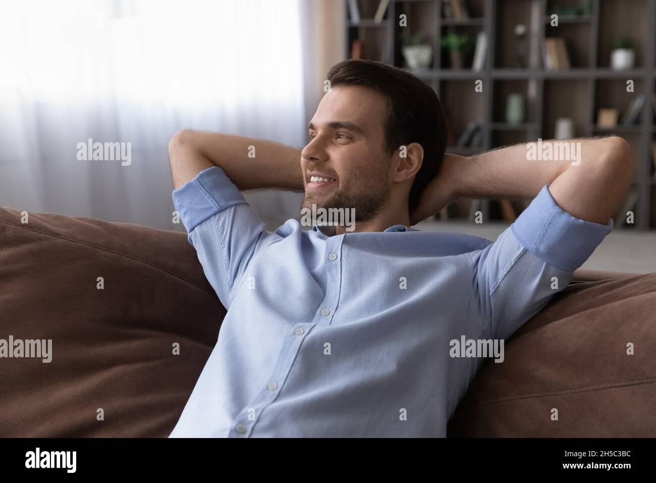 Relaxed young man lying on comfortable sofa. Stock Photo