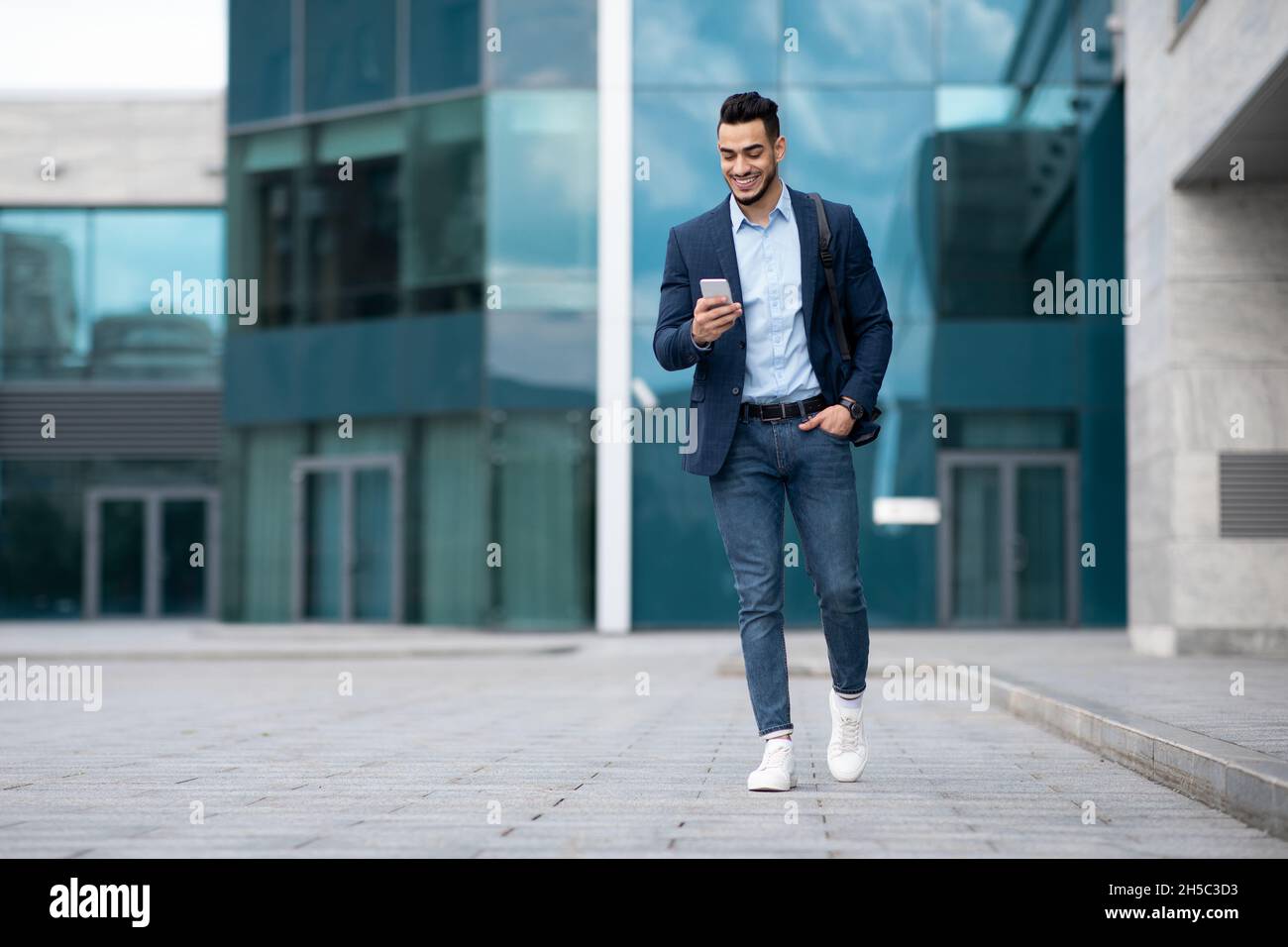 Confident arabic guy programmer with backpack walking by street Stock Photo