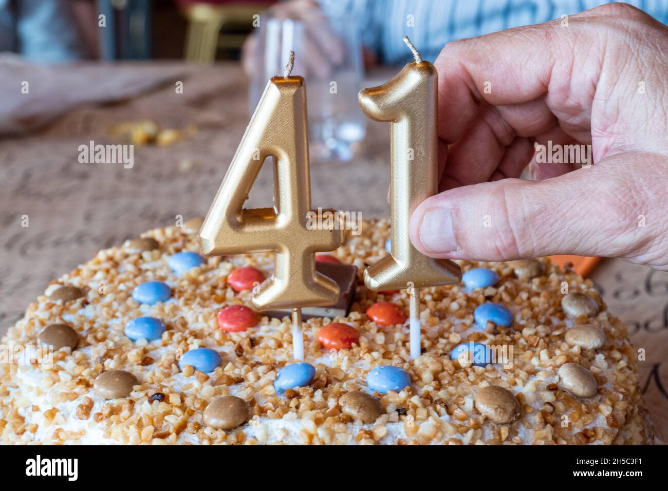 Closeup of a hand Placing numbershaped candles on a birthday cake