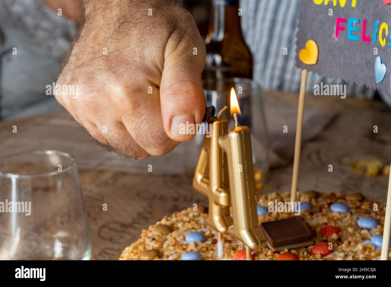 Closeup of a hand Placing numbershaped candles on a birthday cake