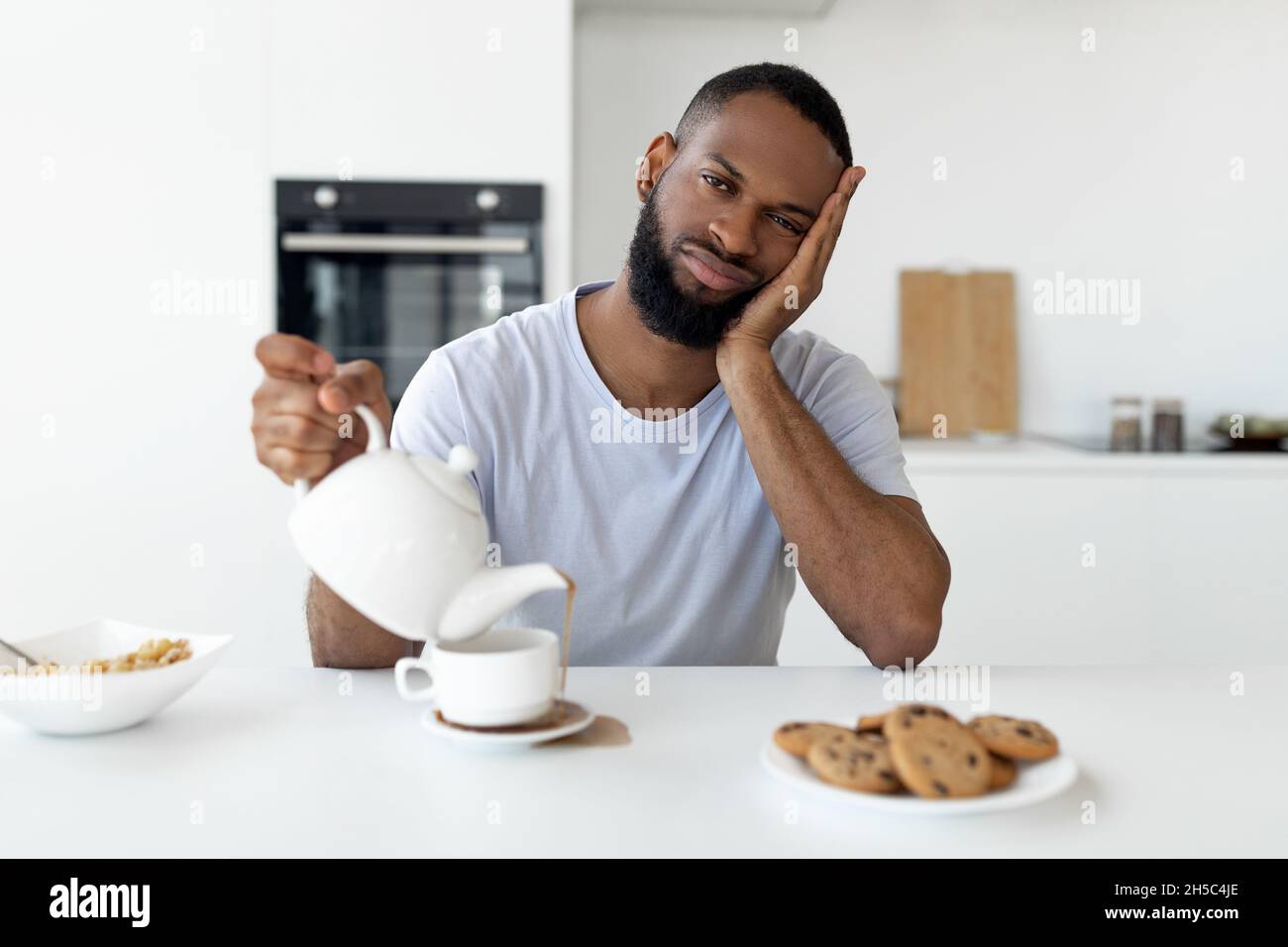 Black guy pouring coffee away from cup spilling hot drink Stock Photo