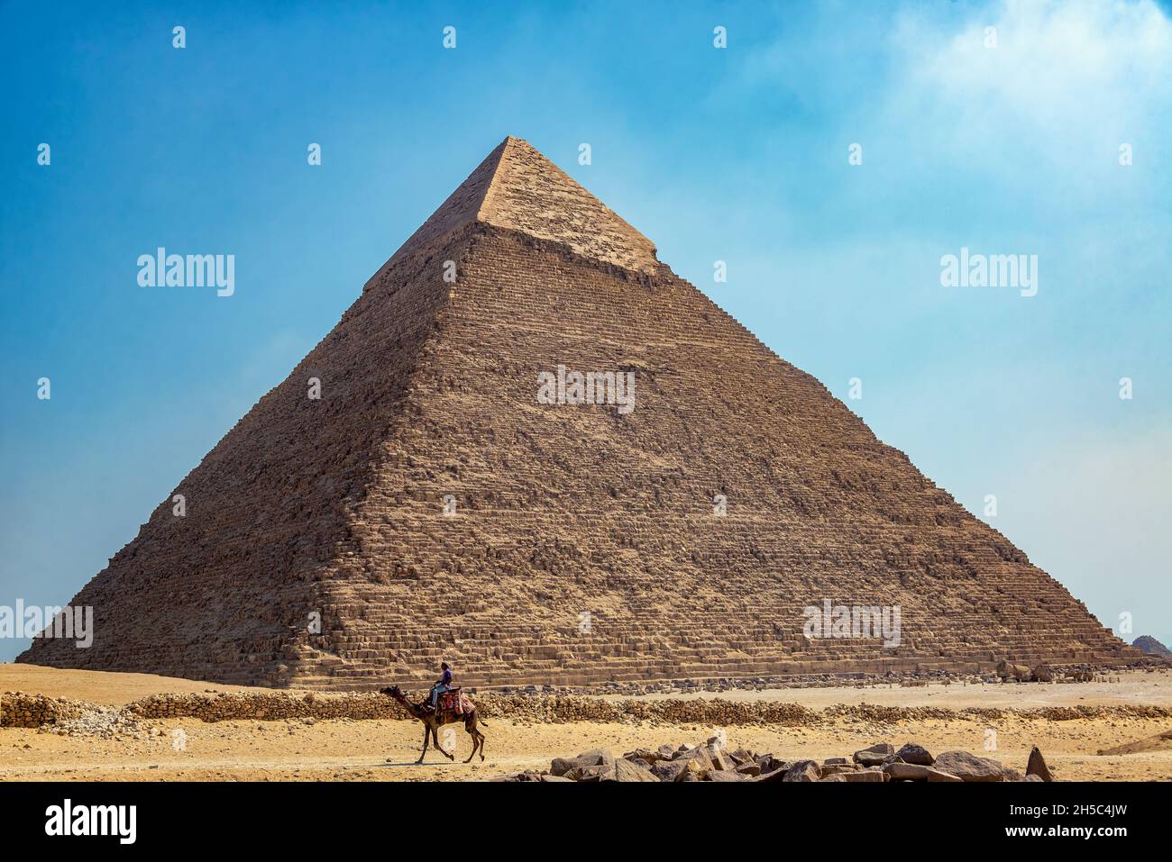 GIZA, EGYPT - JULY 14, 2021: A person rides a camel near the Great Pyramid in Giza, Egypt Stock Photo