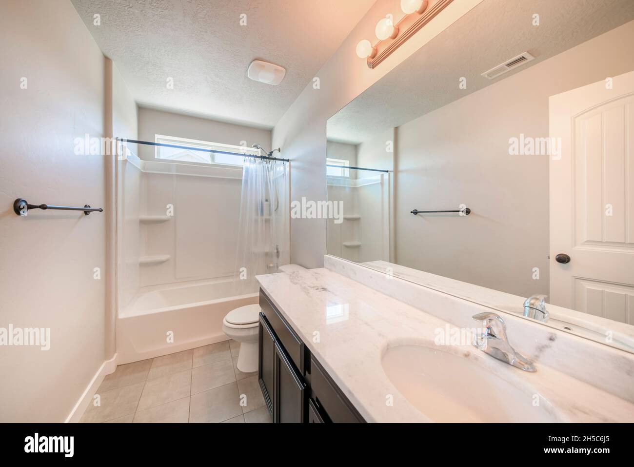 Interior of a white bathroom with black bathroom fixtures and light ...