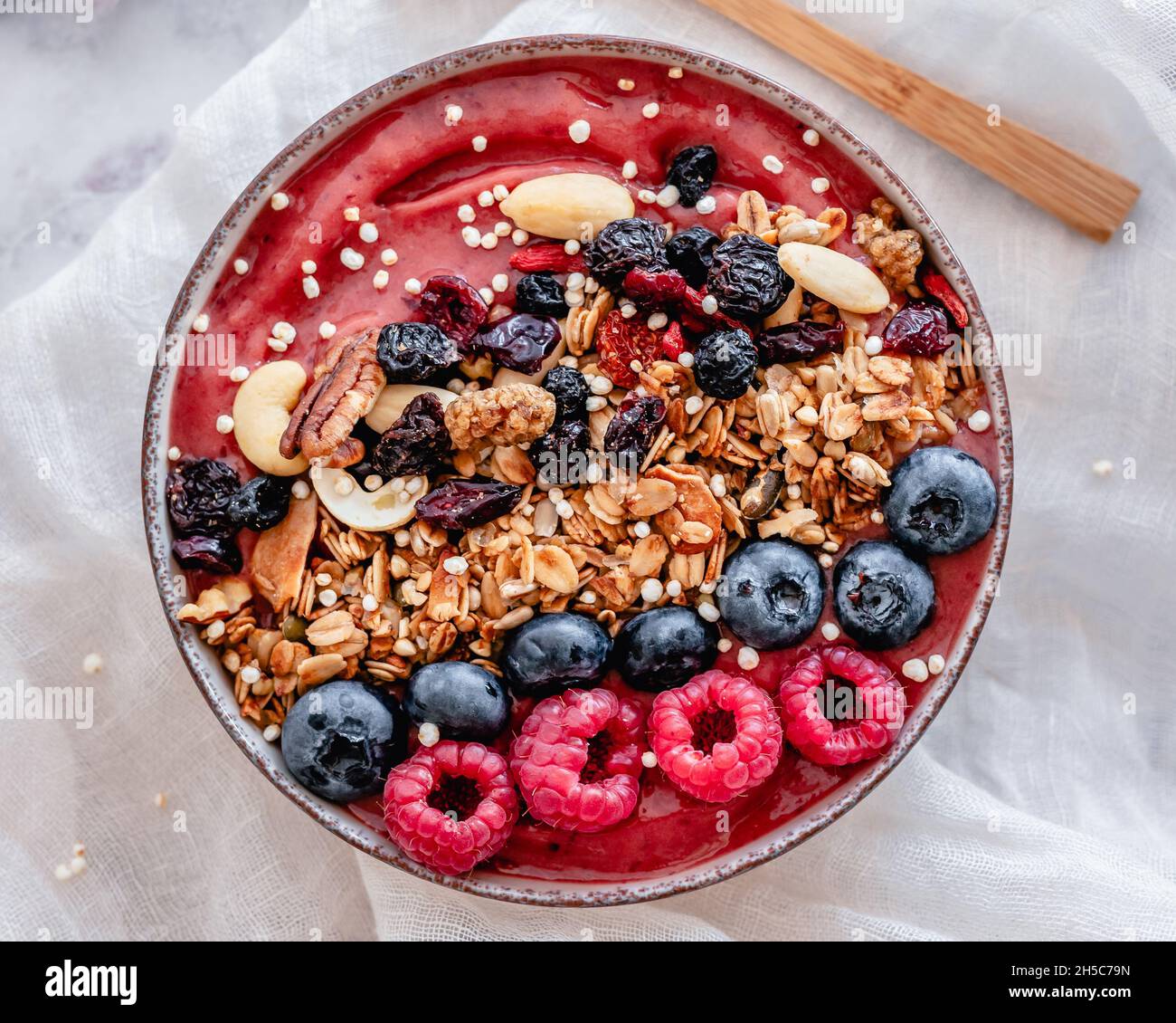 Smoothie bowl with raspberries, blueberries, granola, dried fruits, nuts and puffed quinoa Stock Photo