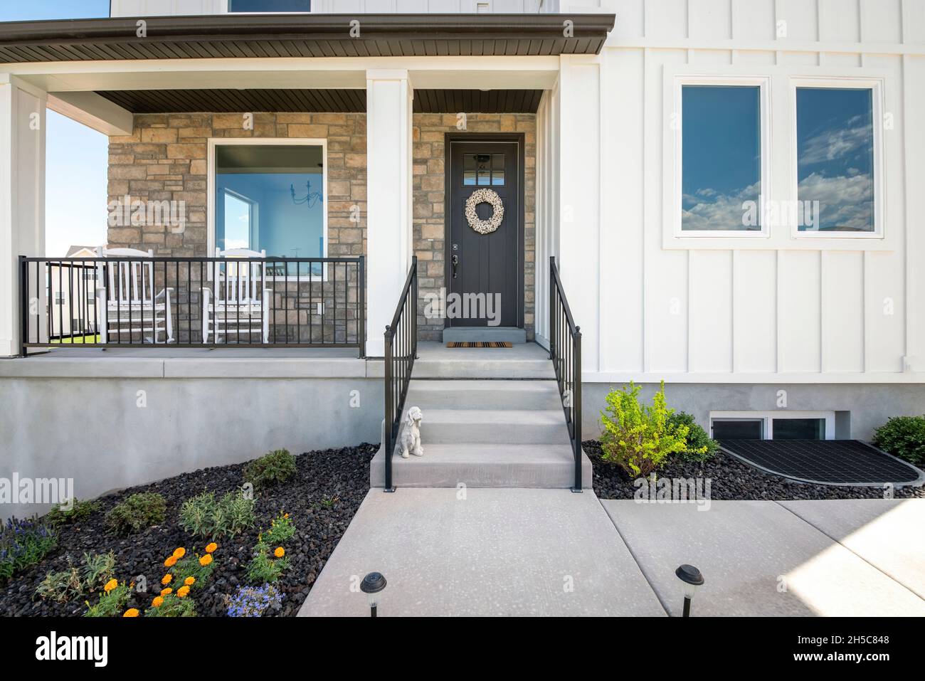 Facade of a house with stone veneer and white board and batten sidings ...