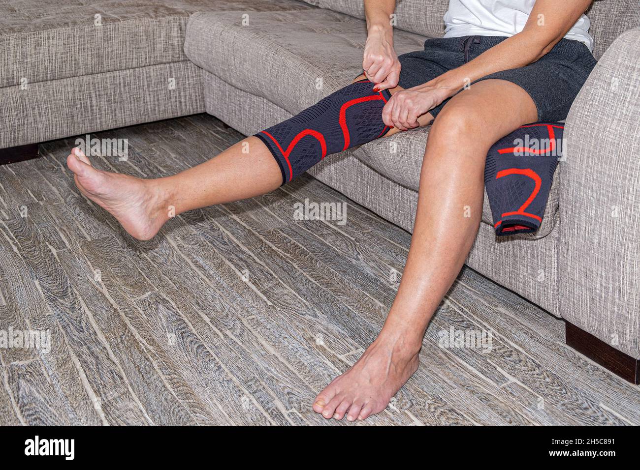 A woman corrects a compression bandage on the knee joint. Arthritis