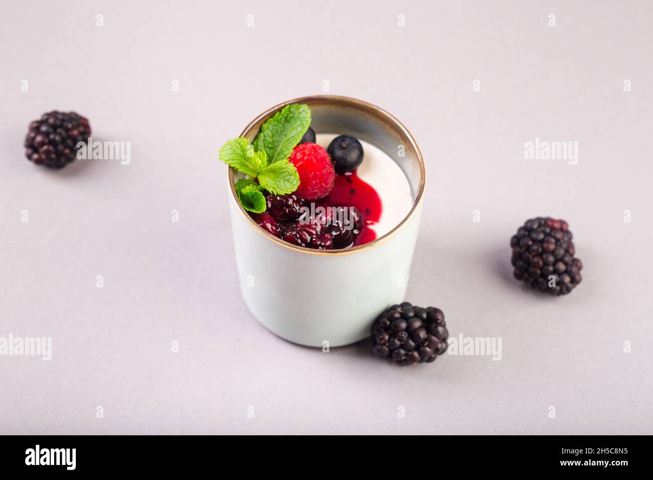 greek yogurt with berries jam and mint in ceramic cup Stock Photo