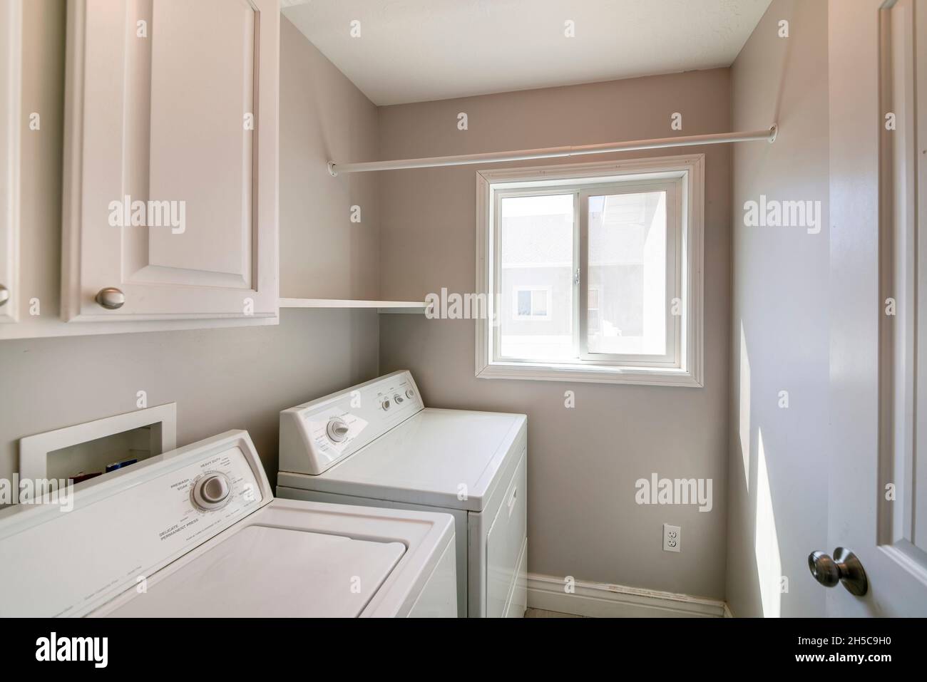 Laundry room interior with light gray wall and white and
