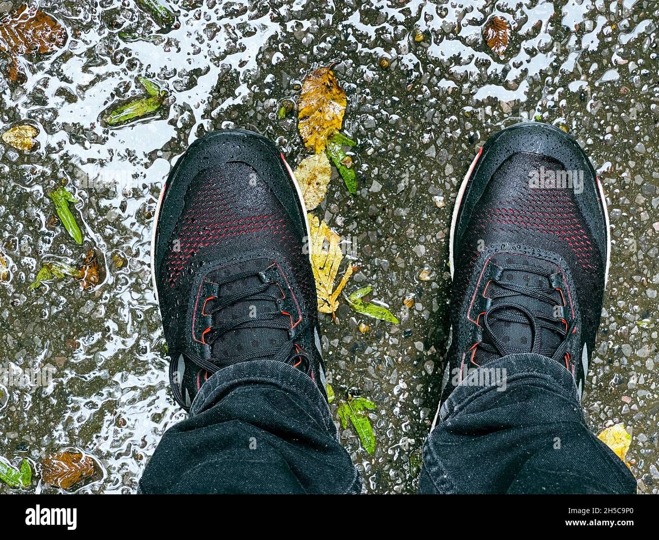 Shoes on the asphalt and lots of rainwater. Stock Photo