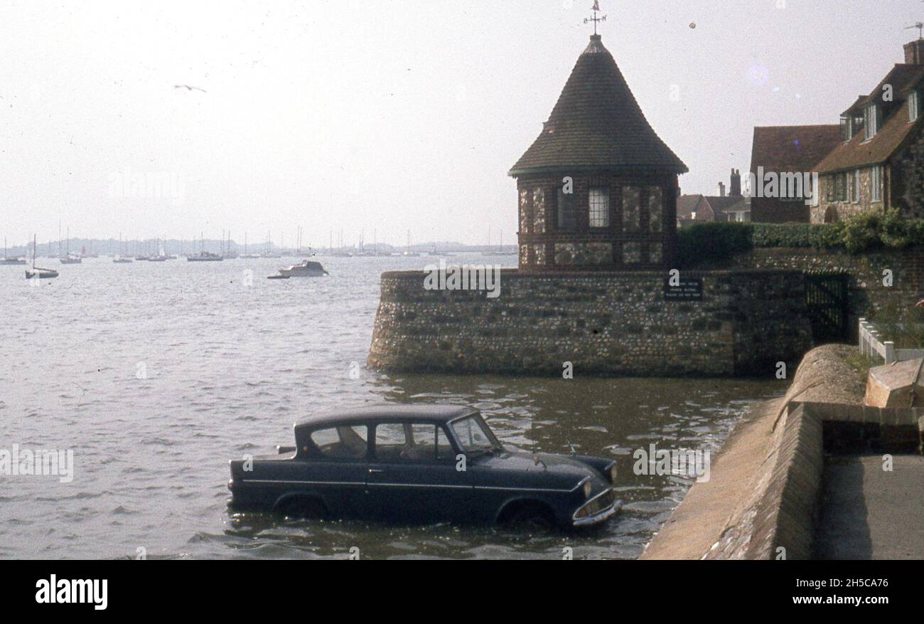 A Ford Anglia seen semi submerged and stranded in the sea, probably caught by the incoming tide. c1970 Photo by Tony Henshaw Archive Stock Photo