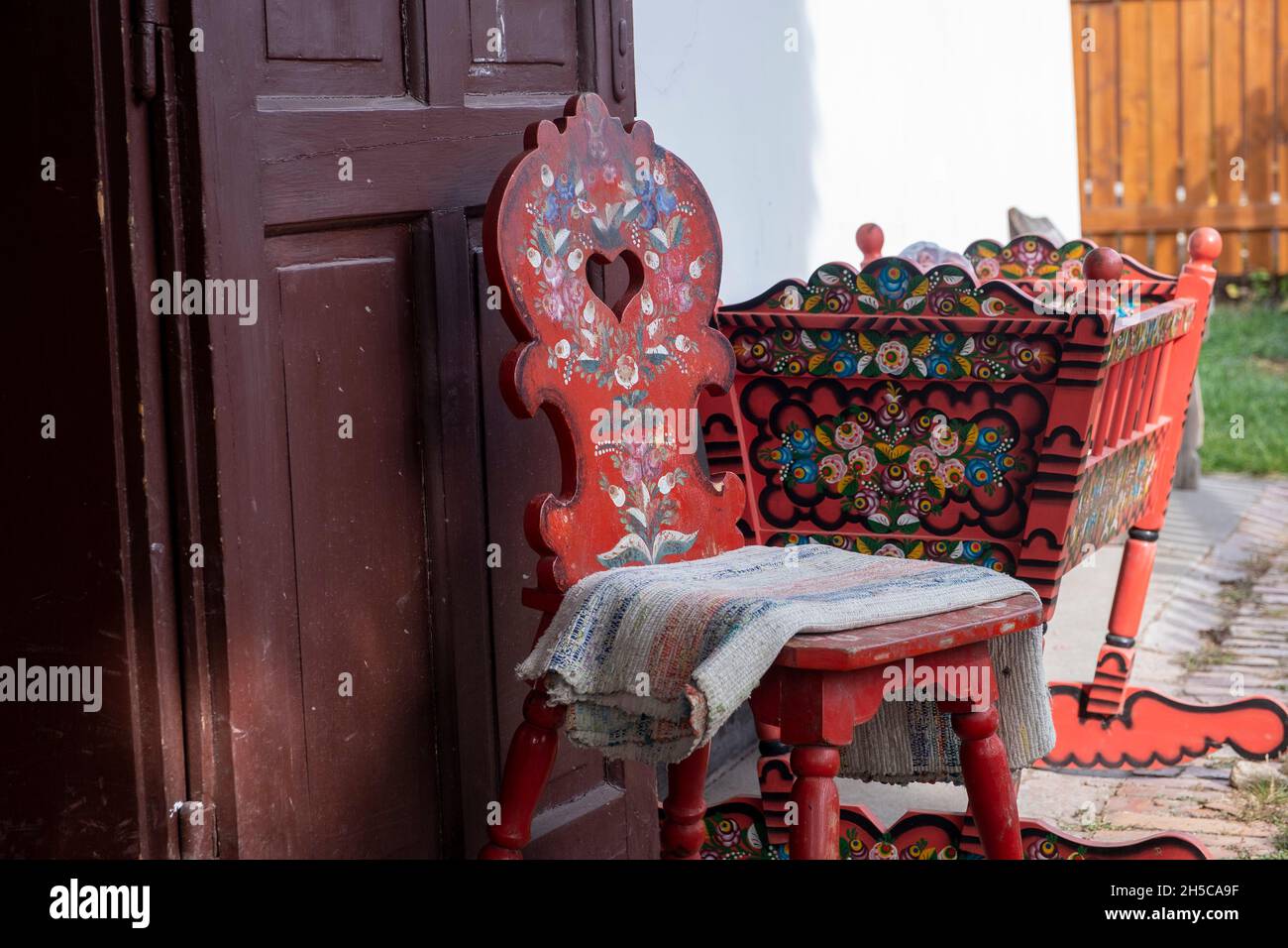 Traditional hungarian motifs painted chair and crib outside a cottage, Mezőkövesd, Hungary Stock Photo