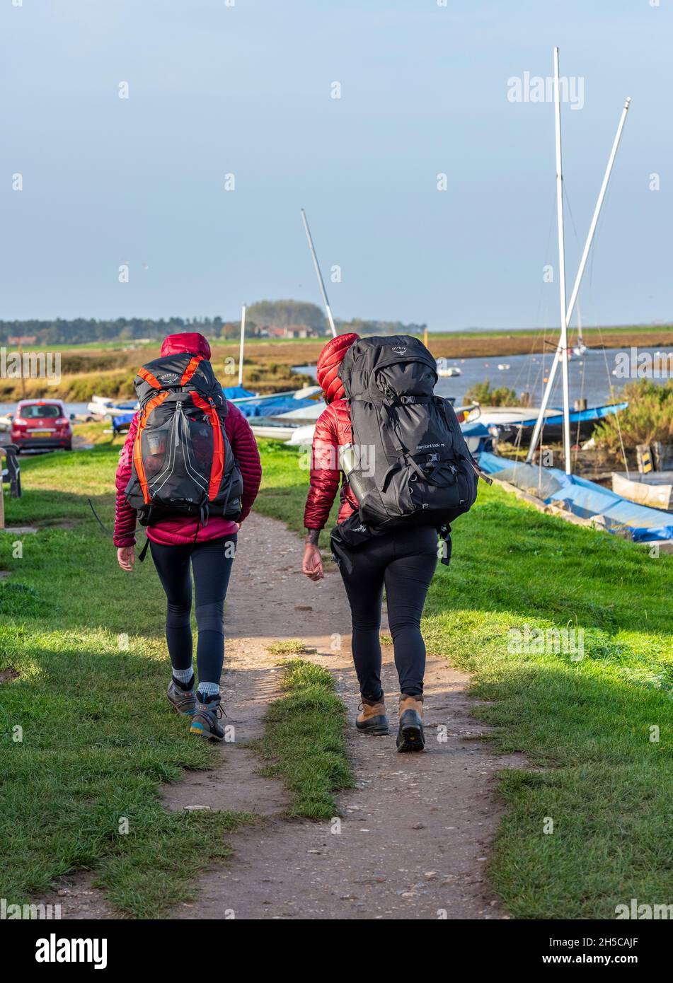 Walk With Rucksack two young women walking together on the norfolk coast at burnham overy ...