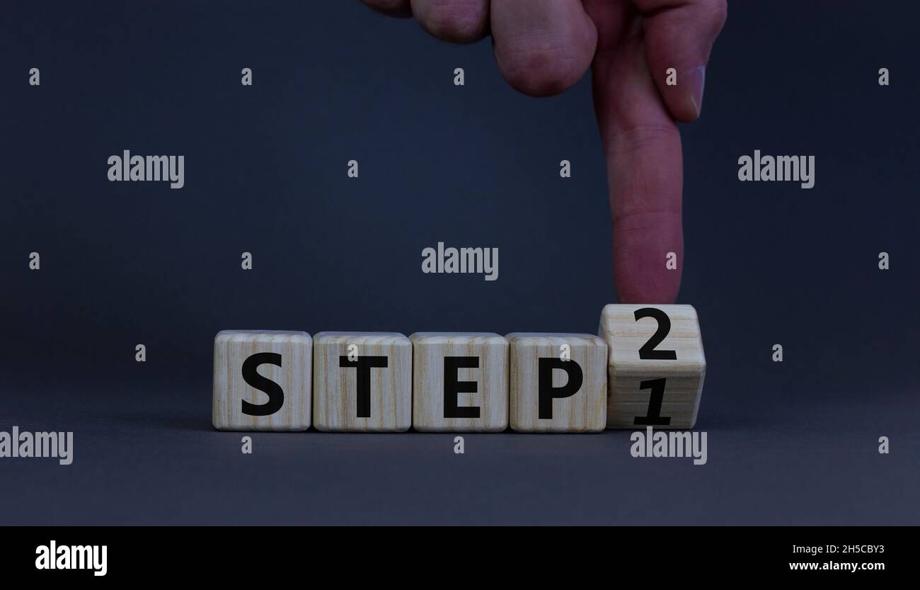 Step 1 or 2 symbol. Businessman turns a wooden cube and changes words ...