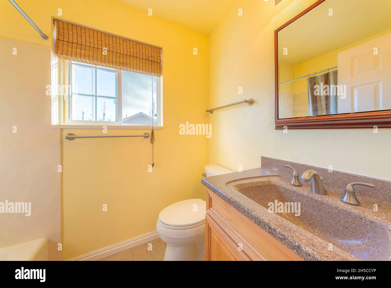 Small yellow bathroom interior with bamboo curtain on the window Stock Photo