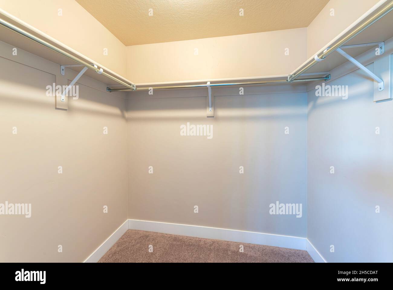 Small walk-in closet with shelves and metal rods below Stock Photo - Alamy